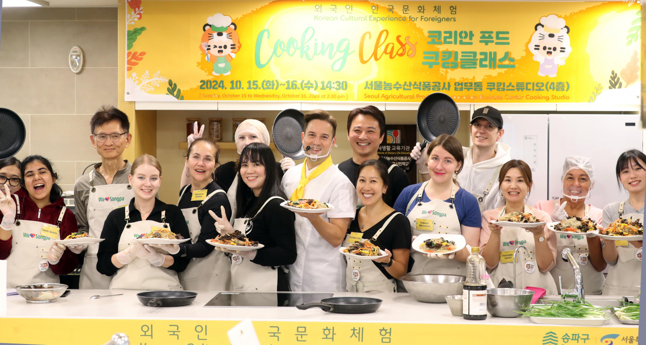 Participants of Songpa-gu Office's Korean Food Cooking Class poses for a photo with Korean-German chef Dario Joseph Lee (fifth from left) at Garak Mall's cooking studio on Wednesday. (Songpa-gu Office)