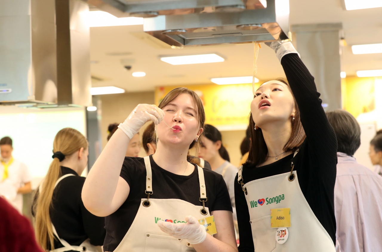 Participants of Songpa-gu Office's Korean Food Cooking Class taste their japchae at a cooking studio in Garak Mall on Wednesday. (Songpa-gu Office)