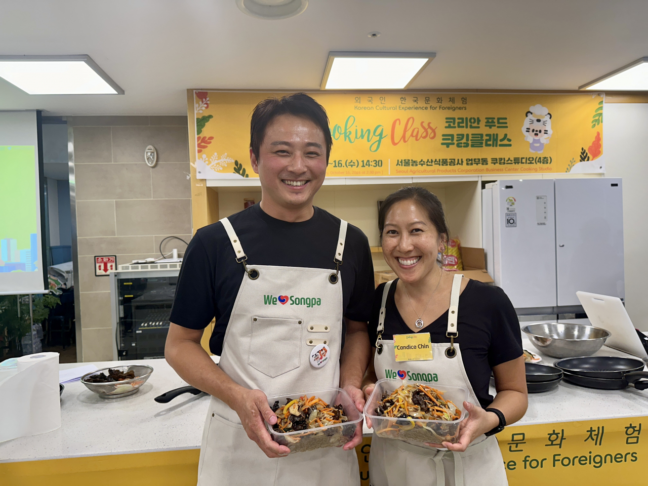 Candice Chin (right) poses for a photo with the japchae that she made with her partner, Huang Yin Kai, during the Korean Food Cooking Class hosted by Songpa-gu Office at a cooking studio in Garak Mall on Wednesday. (Lee Jung-joo/The Korea Herald)