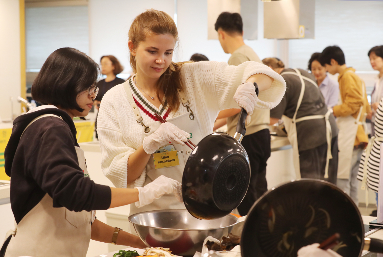 Participants of Songpa-gu Office's Korean Food Cooking Class make japchae together at a cooking studio in Garak Mall on Wednesday. (Songpa-gu Office)