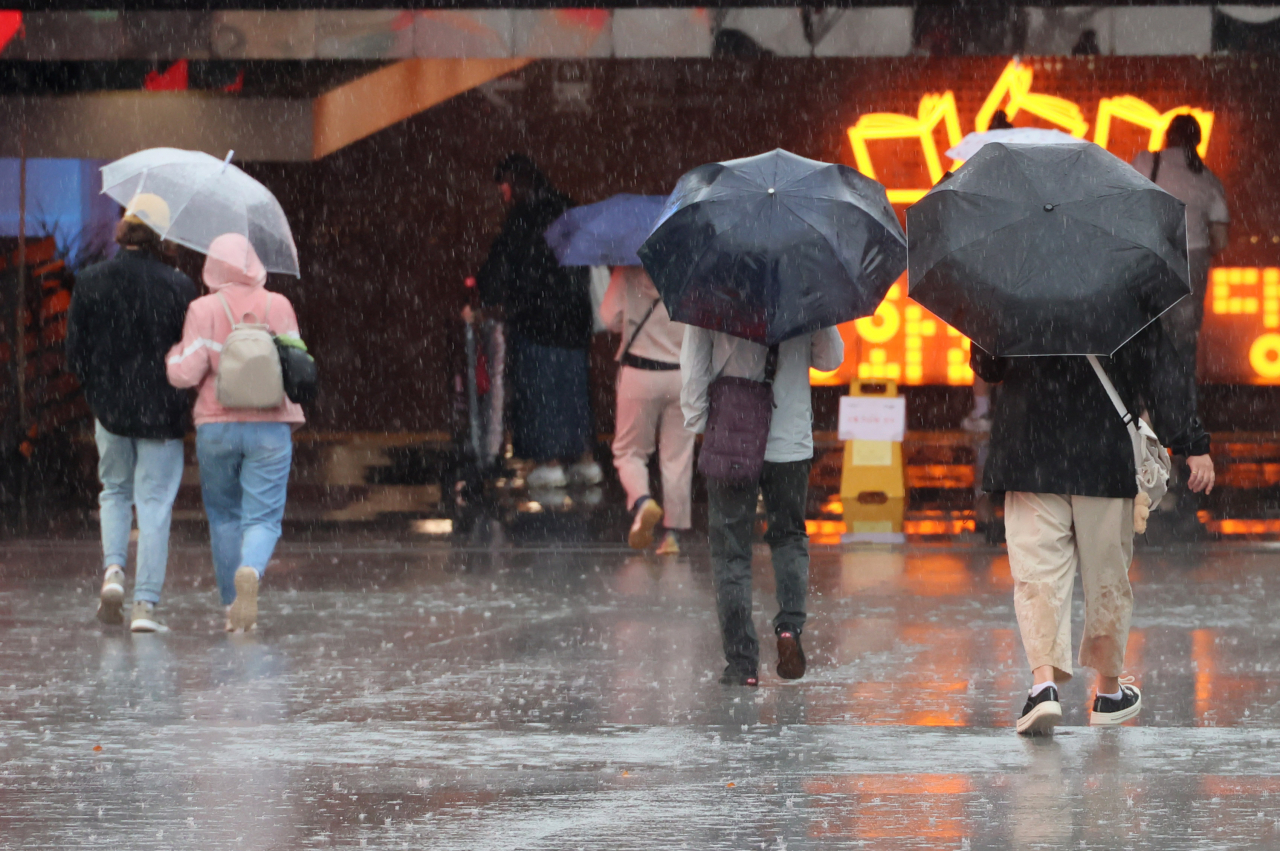 Pedestrians walk through the rain with umbrellas near Gwanghwamun Square in central Seoul on Friday. (Yonhap)