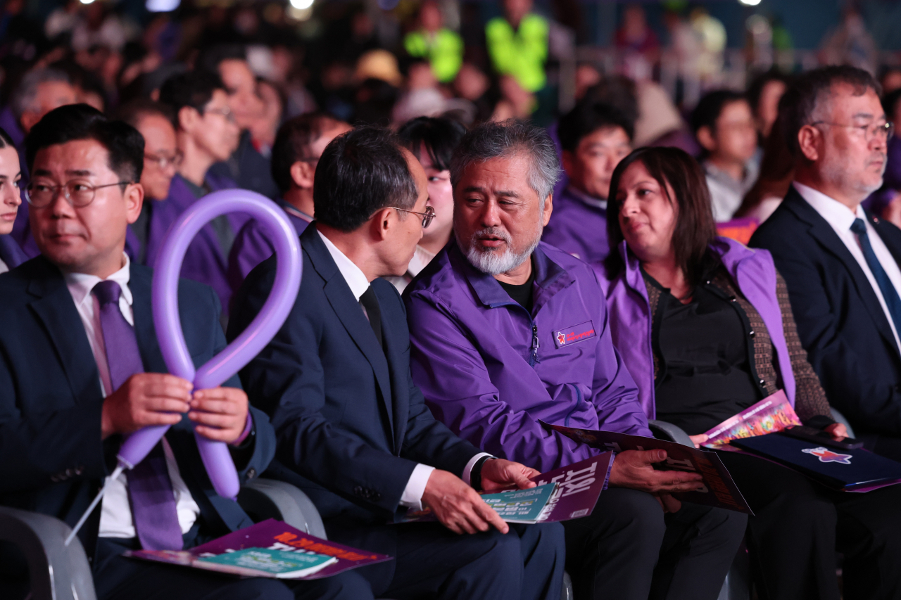 Ruling People Power Party floor leader Choo Kyung-ho (2nd from left) speaks with Lee Jeong-min (center), head of the group representing the bereaved families of the victims of the 2022 Itaewon crowd crush that claimed 159 lives during Halloween celebrations, at a memorial event in front of Seoul City Hall marking the tragedy's second anniversary, on Saturday. (Yonhap)