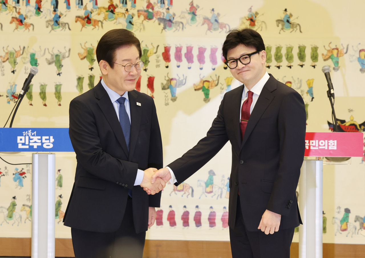 Democratic Party of Korea Chair Lee Jae-myung, left, shakes hands with People Power Party Chair Han Dong-hoon ahead of their first official talks held at the National Assembly in western Seoul in September. (Yonhap)