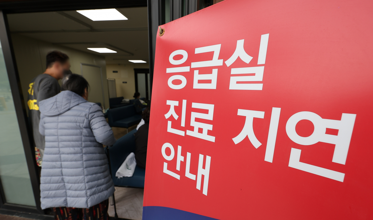 A sign notifying visitors about delays in treatment stands at the entrance of an emergency room in Seoul on Sunday. (Yonhap)