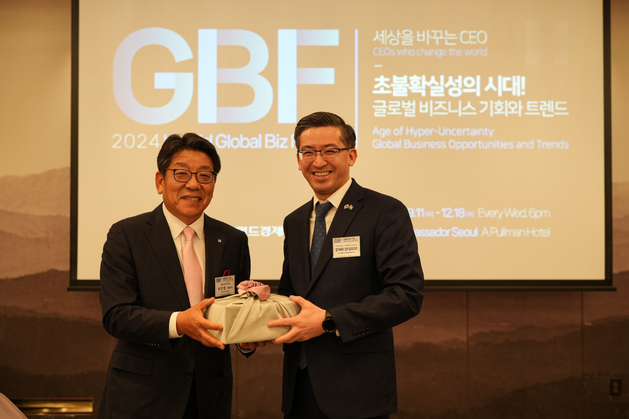 Uzbek Ambassador to South Korea Alisher Abdusalomov (right) poses with Herald Media Group CEO Choi Jin-young, gifting him a souvenir after Abdusalomov's speech at the Global Business Forum held in Seoul on Wednesday. (The Korea Herald)