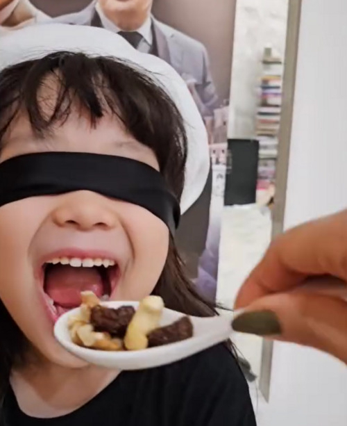 A screenshot of a video showing Paik’s daughter mimicking Paik's blind tasting moment in 