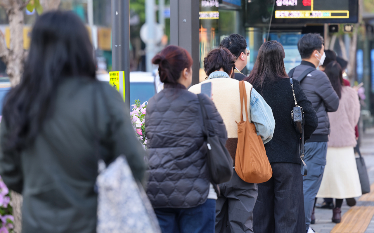 Commuters wait for the bus in thick autumn clothing near Gwanghwamun in Jongno-gu, central Seoul. (Yonhap)