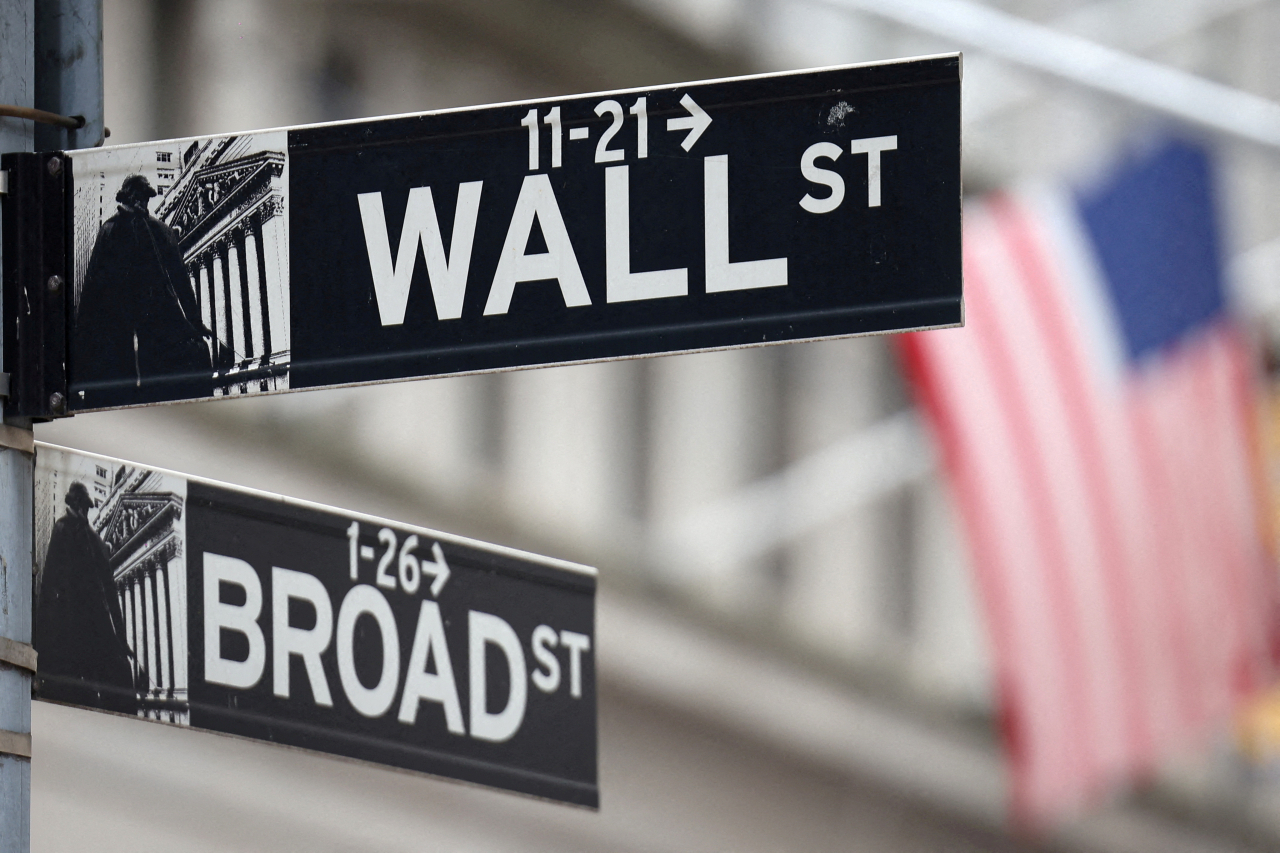 A Wall Street sign hangs in front of a US Flag outside the New York Stock Exchange in New York City on Sept. 18. (Reuters-Yonhap)