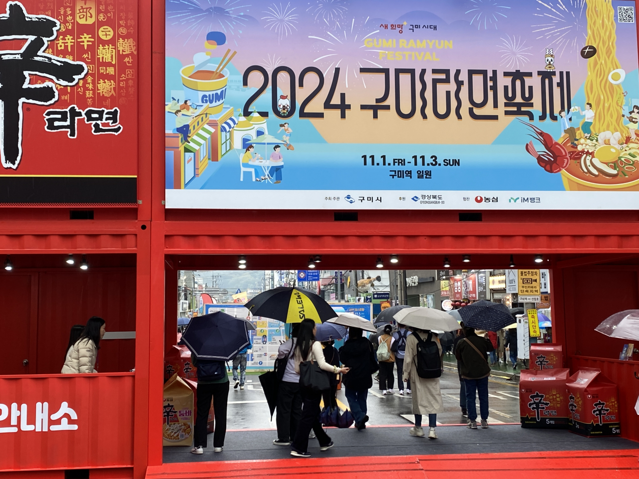 Visitors pass through the two-story red container gate adorned with promotional posters for the Gumi Ramyun Festival and Nongshim's flagship product, Shin Ramyun, in Gumi, North Gyeongsang Province, Friday. (Hwang Joo-young/The Korea Herald)