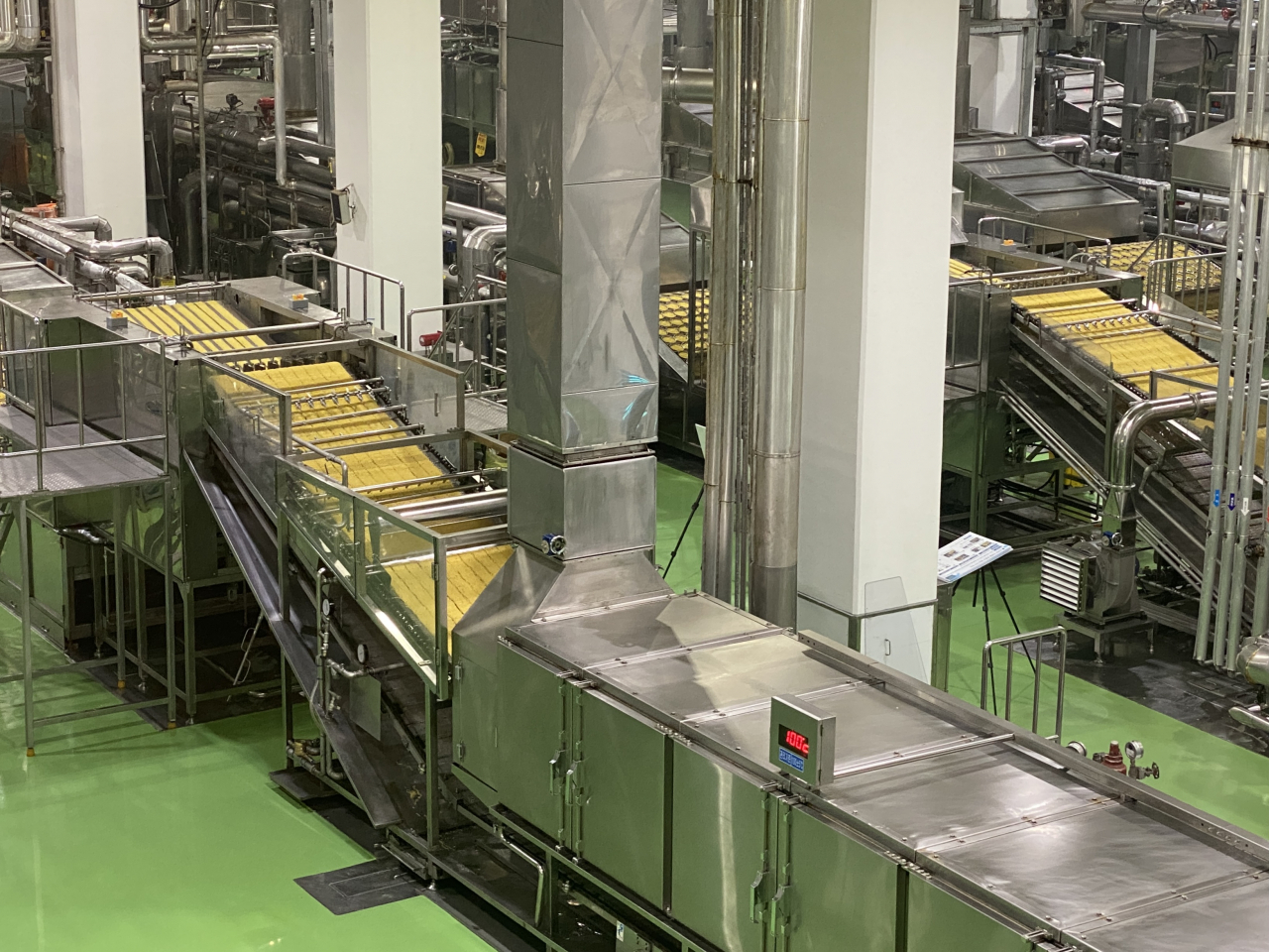 Steamed noodles are conveyed to machines where they are cut and shaped at the Nongshim Gumi plant. (Hwang Joo-young/The Korea Herald)