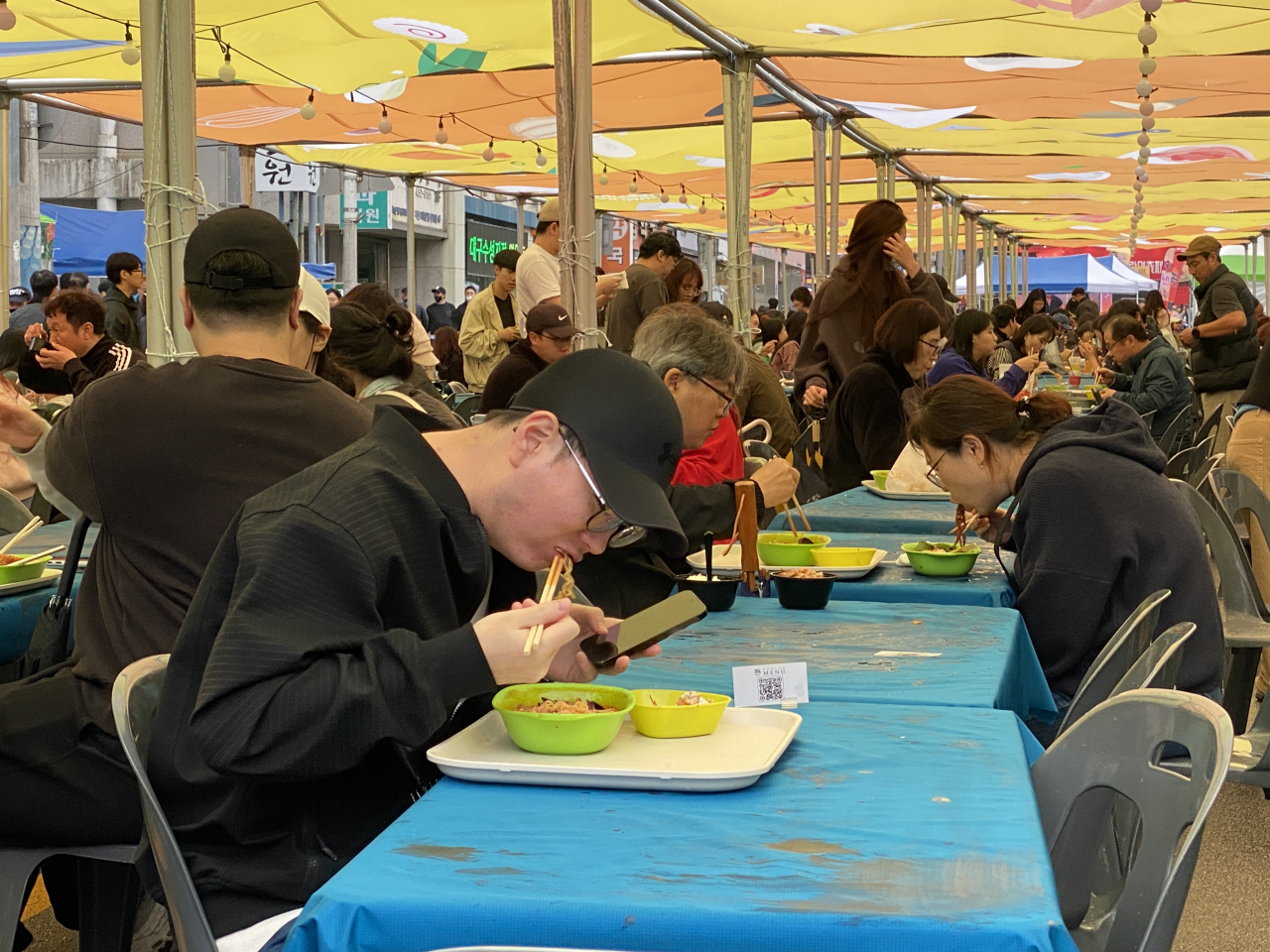 Visitors at the Gumi Ramyun Festival enjoy dishes under a canopy. (Hwang Joo-young/The Korea Herald)