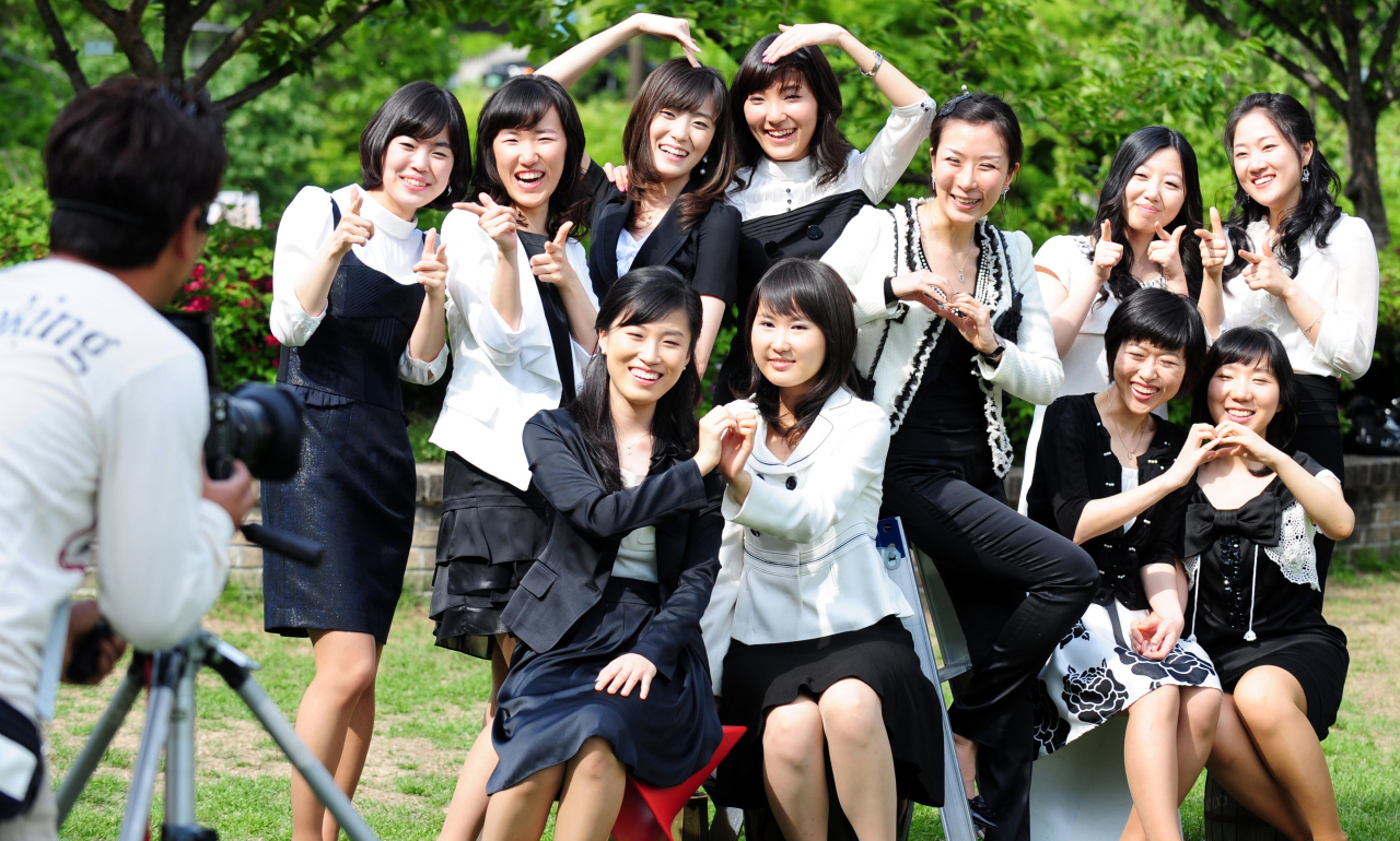 Amid the vibrant May greenery, female students laugh and pose for their graduation album photos, adding a refreshing energy to the campus. (Korea Herald)