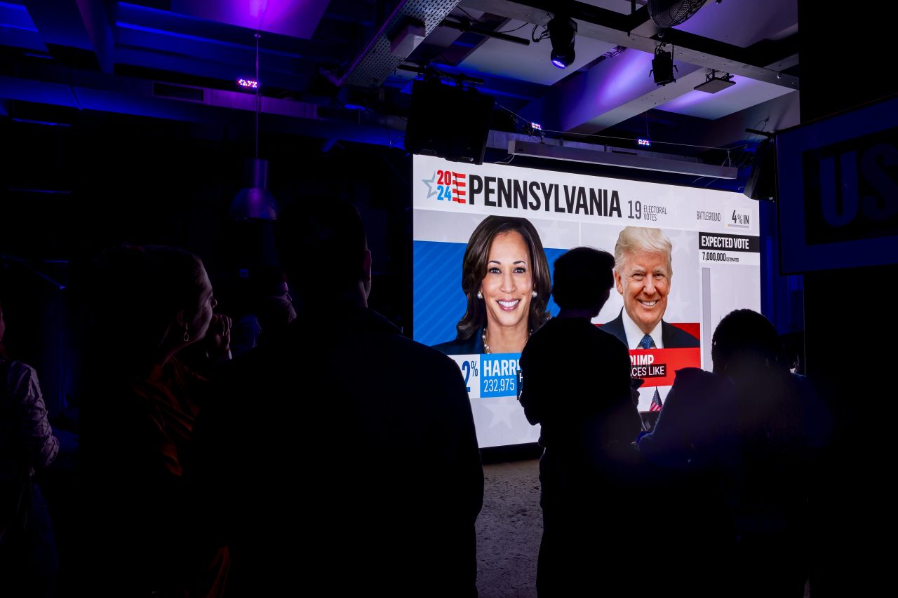 Supporters of Democratic presidential nominee Vice President Kamala Harris look at the first results, during the US election night party, in Geneva, Switzerland, Tuesday. (EPA-Yonhap)