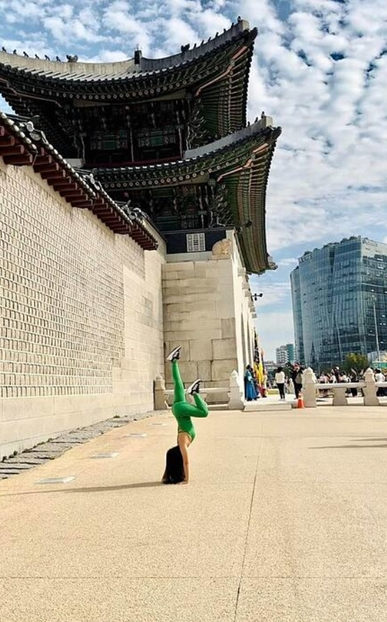 This photo, captured from VnExpress International, shows a woman practicing yoga in front of Gyeongbokgung in Seoul.