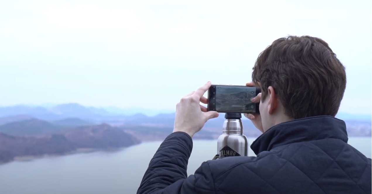 A screenshot from a video showing a man taking a photo of North Korea at Aegibong Peace Ecopark, posted on The Herald Business's official YouTube channel (YouTube)