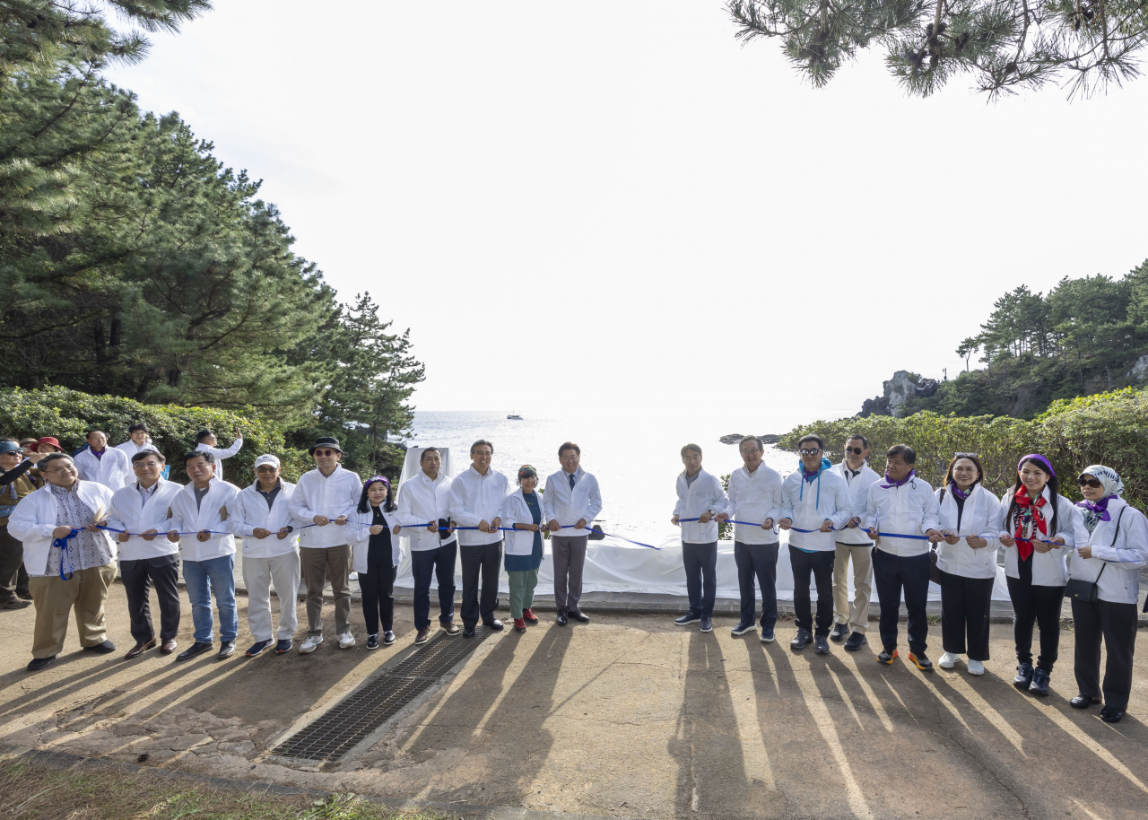 Participants at the Jeju Olle Trail 8 Route: ASEAN-Korea Olle unveiling ceremony, including Korea-ASEAN Center Secretary-General Kim Jae-shin (11th from left), Jeju Island Gov. Oh Young-hun (10th from left), actor Ryu Seung-ryong (13th from left) and ambassadors representing Southeast Asian countries, pose for a photo in front of a concrete bench to commemorate the 35th anniversary of dialogue relations between South Korea and the Association of Southeast Asian Nations on Friday. (Korea-ASEAN Center)