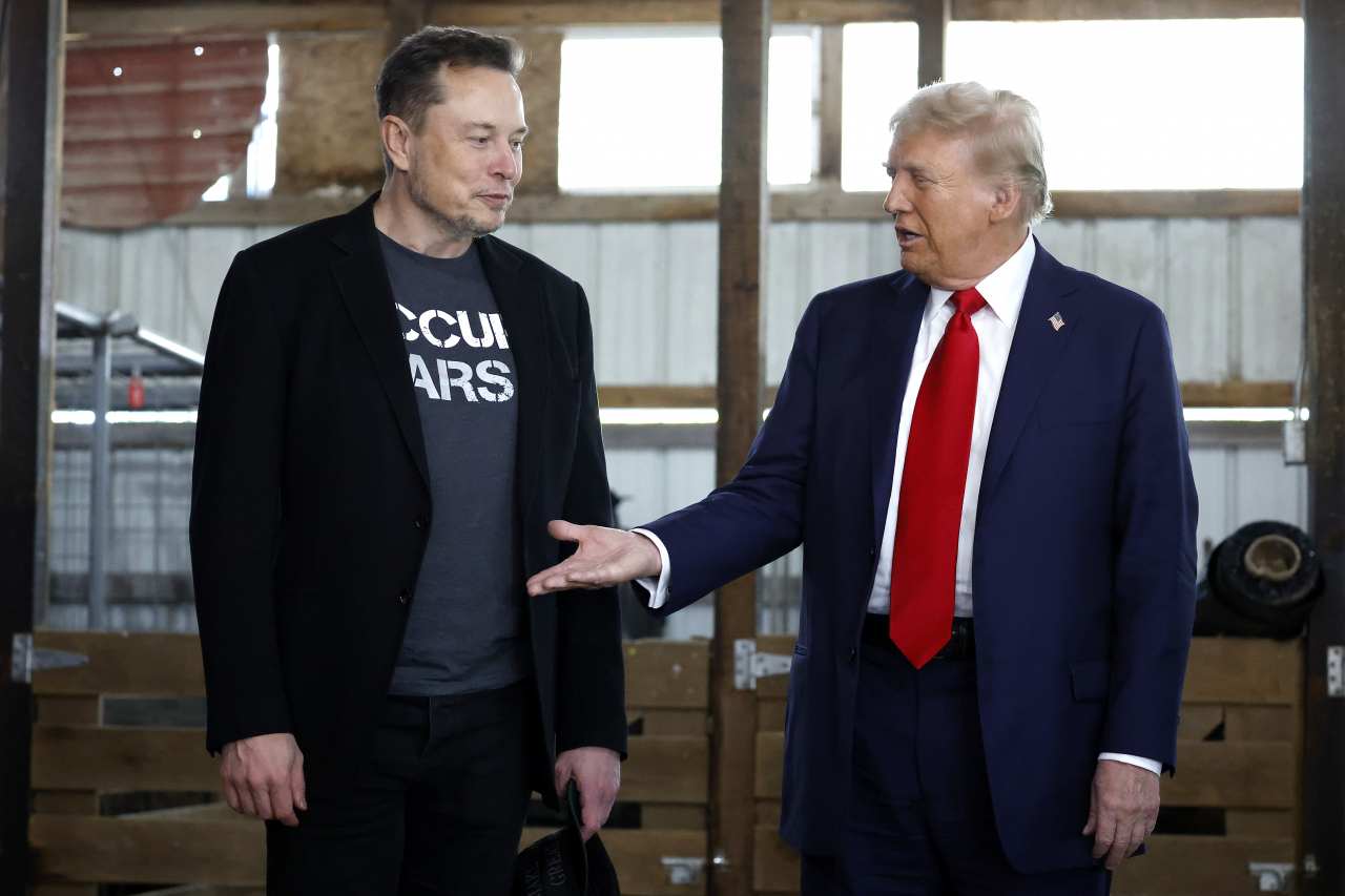 Republican presidential nominee, former President Donald Trump offers his hand to Elon Musk back stage during a campaign rally at the Butler Farm Show grounds on Oct. 5 in Butler, Pennsylvania. (Getty Images)