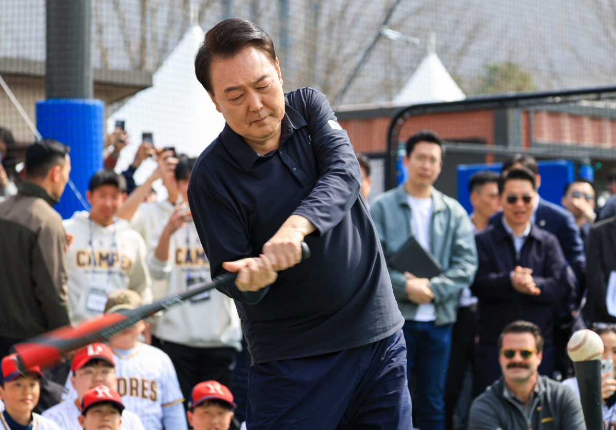 President Yoon Suk Yeol swings a baseball bat as he invited children and professional baseball players of San Diego Padres based in San Diego, Calif. in March at a park near Yoon;s office in Seoul. (Presidential office)