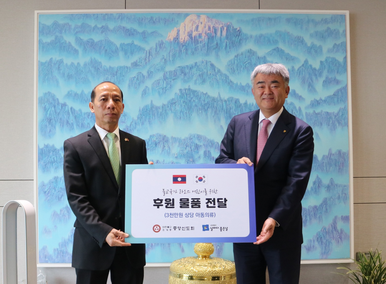 Jung Won-ju (right), chairman of Herald Media Group and Daewoo E&C, and Alounkone Boulommavong, deputy chief of mission of the Laotian Embassy in South Korea, pose for a photo at a donation ceremony in Seoul on Thursday. (Lay Buddhist Association of the Jogye Order of Korean Buddhism)