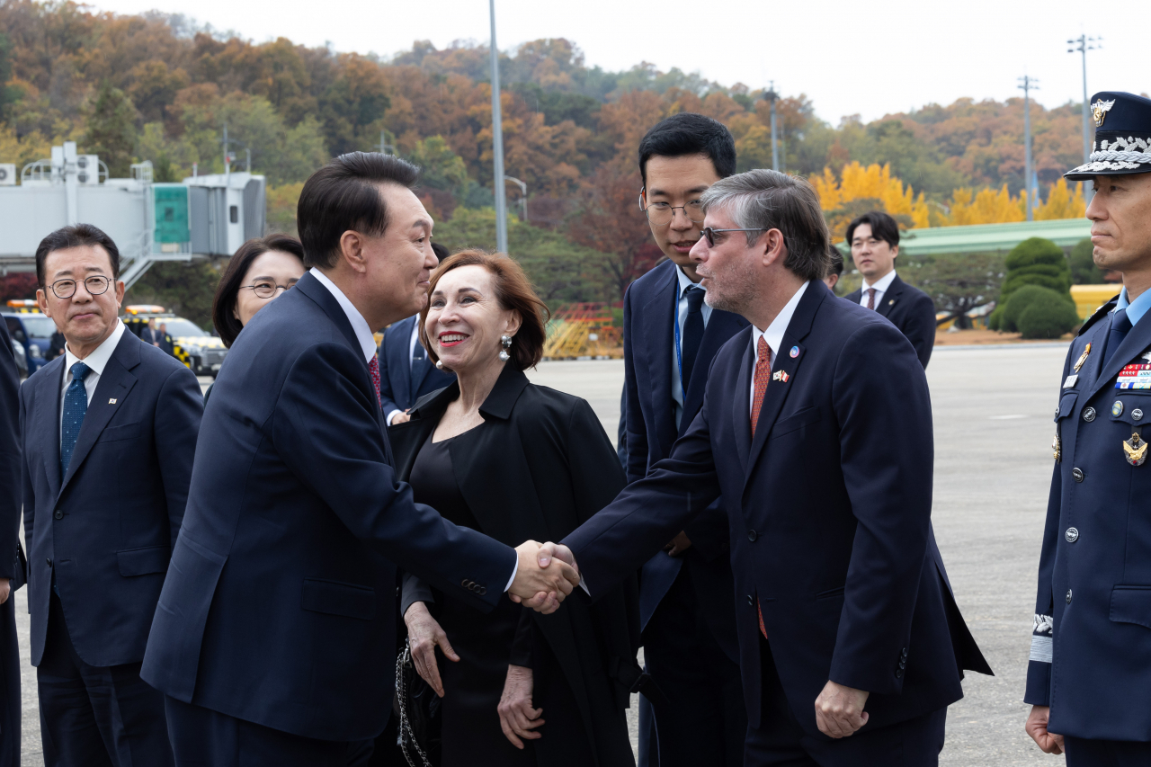 In this photo provided by the presidential office, President Yoon Suk Yeol (2nd from left) shakes hands with Paulo Fernando Duclos Parodi (2nd from right), the Peruvian ambassador to South Korea, at Seoul Air Base in Seongnam, south of Seoul, on Nov. 14, Thursday, before departing for Peru to attend the Asia-Pacific Economic Cooperation summit. (Yonhap)