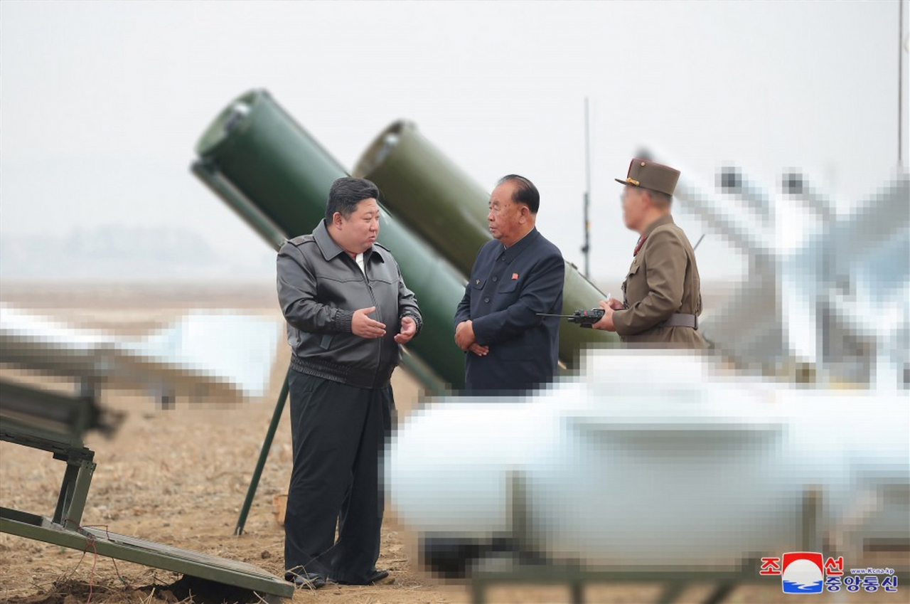 North Korean leader Kim Jong-un (left) speaks with Ri Pyong-chol (center), vice-chairman of the Central Military Committee, while supervising a performance test of suicide attack drones produced by an institute affiliated with the Unmanned Aerial Technology Complex and other enterprises, on Thursday, in this photo provided by the state-run Korean Central News Agency on Friday. Yonhap