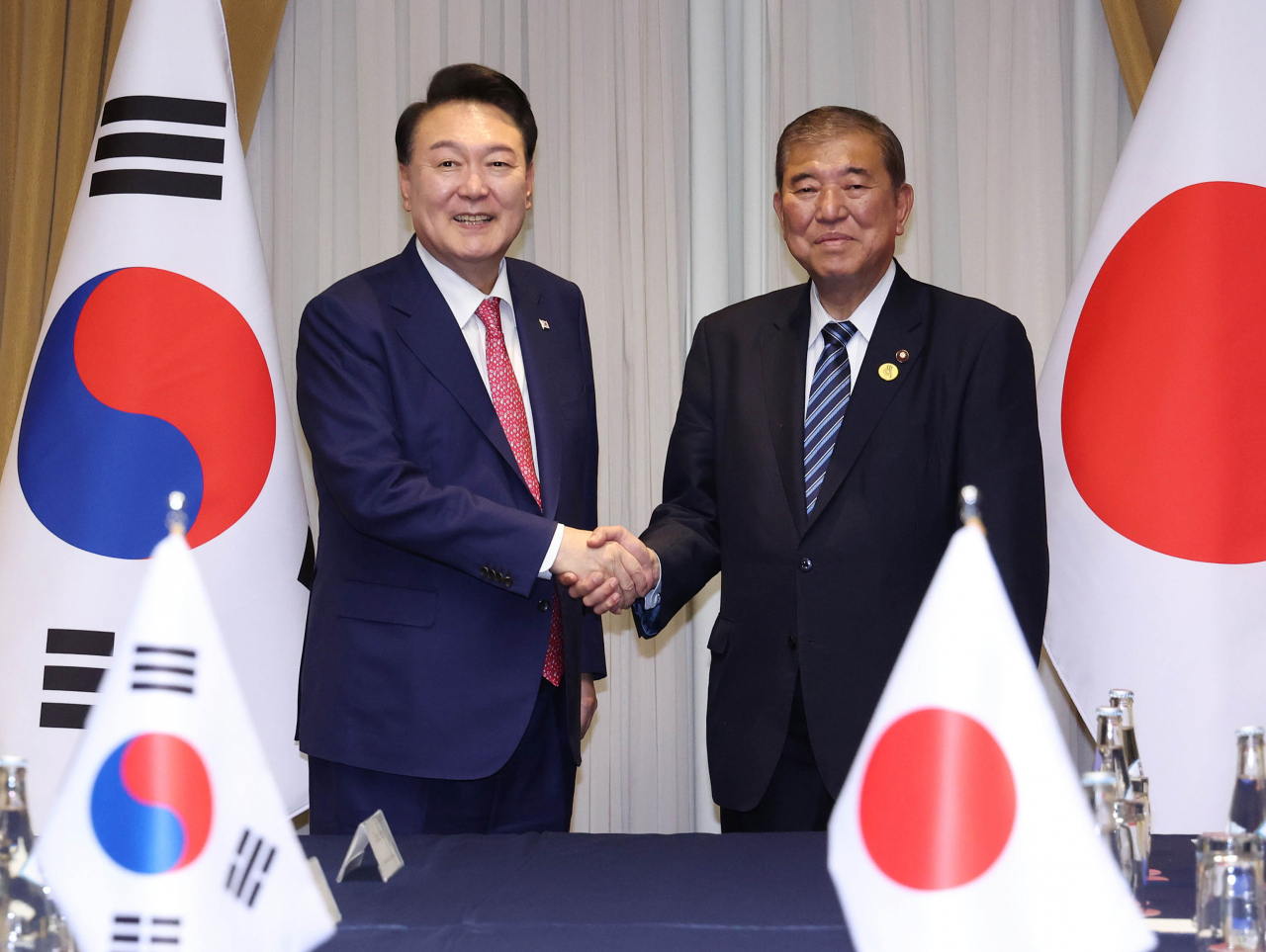 President Yoon Suk Yeol (left) shakes hands with Japanese Prime Minister Shigeru Ishiba during their meeting at a hotel in Lima, Peru on Saturday. (Yonhap)