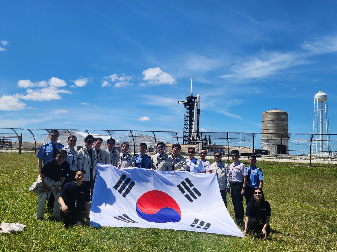 South Korea officials hold a Korean national flag as they pose for a photograph as the second military reconnaissance satellite prepares to launch at the Kennedy Space Center in Florida, US, in April. (Ministry of National Defense)