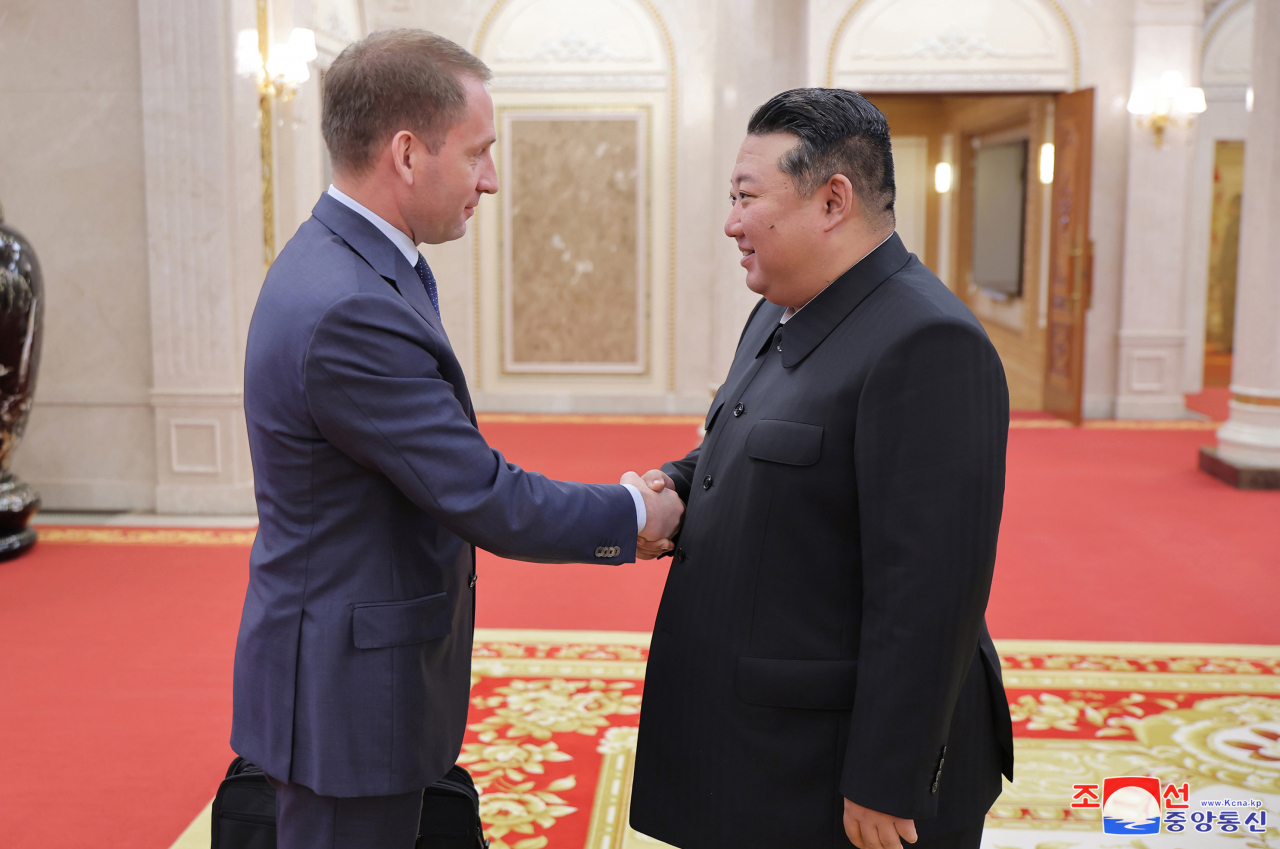 North Korean leader Kim Jong-un (right) shakes hands with Russian Minister of Natural Resources and Ecology Alexander Kozlov on Tuesday. (KCNA)