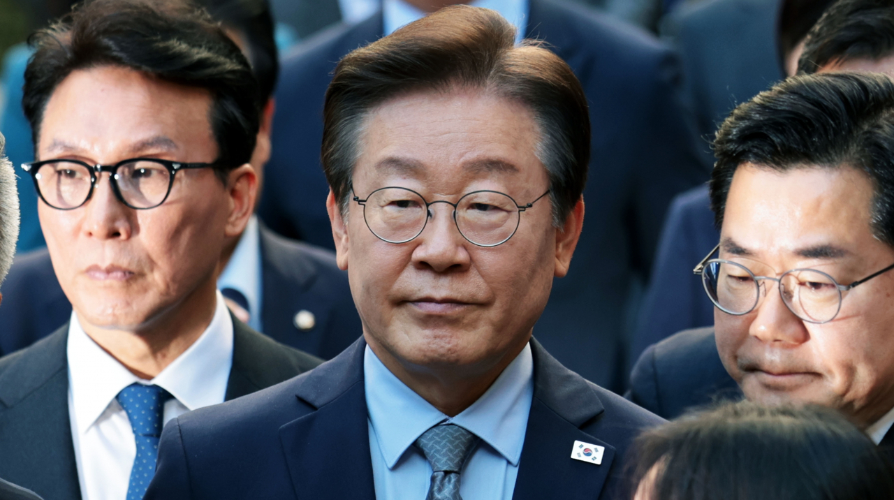 Opposition leader Lee Jae-myung (center) leaves the Seoul Central District Court in southern Seoul on Friday after the court's sentencing on his election law violation charges. (Yonhap)