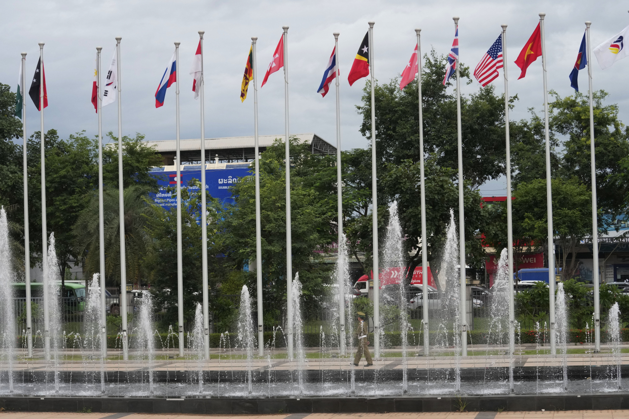 A police officer walks along flags of nations participating in the meetings of the Association of Southeast Asian Nations (ASEAN) at the national convention center in Vientiane, Laos, Wednesday, July 24, 2024. (AP Photo/Sakchai Lalit, File)