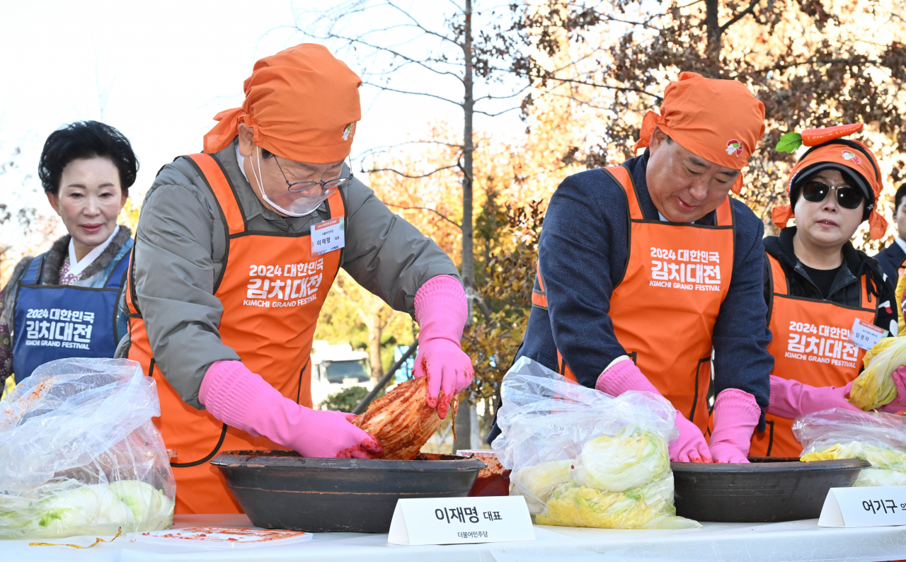 Democratic Party of Korea's leader Lee Jae-myung (left) and Rep. Eoh Kiy-ku make kimchi on Friday. (Im Se-jun/The Korea Herald)