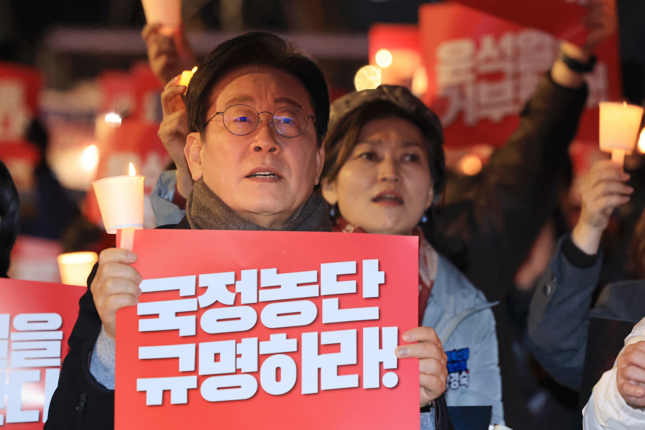 Lee Jae-myung, chair of the main opposition Democratic Party, holds up a placard during a mass rally in central Seoul on Saturday, demanding an independent counsel investigation into allegations involving first lady Kim Keon Hee. (Yonhap)