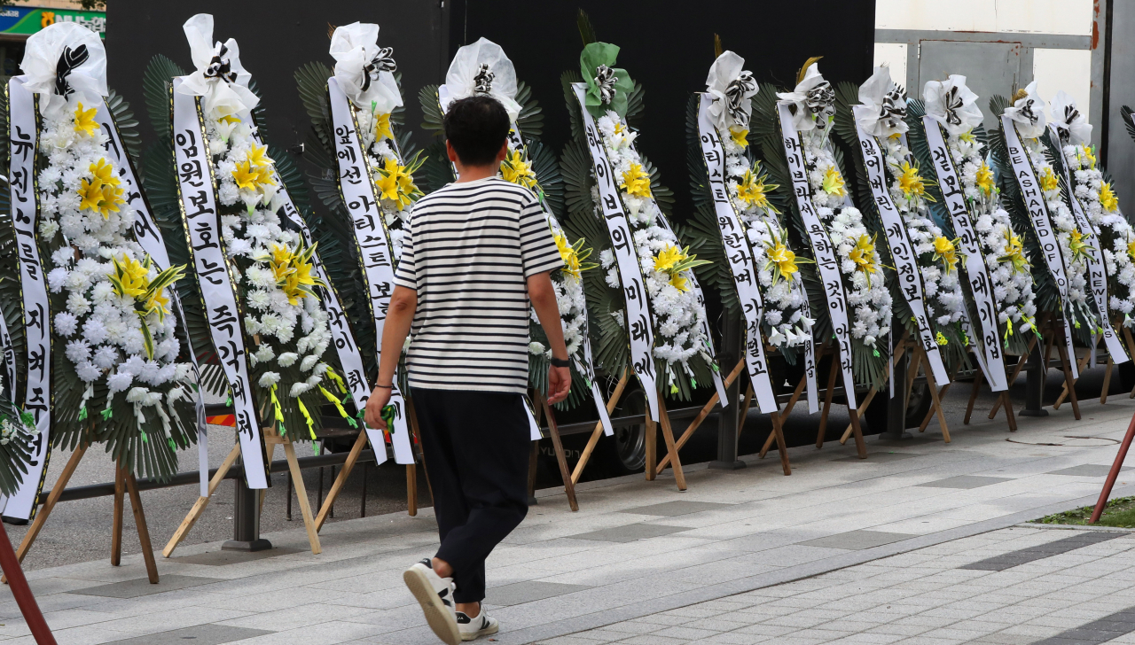 A pedestrian walks by funeral wreaths sent by Bunnies, NewJeans' fanbase, to the Hybe’s headquarters in Seoul, in September. (Newsis)