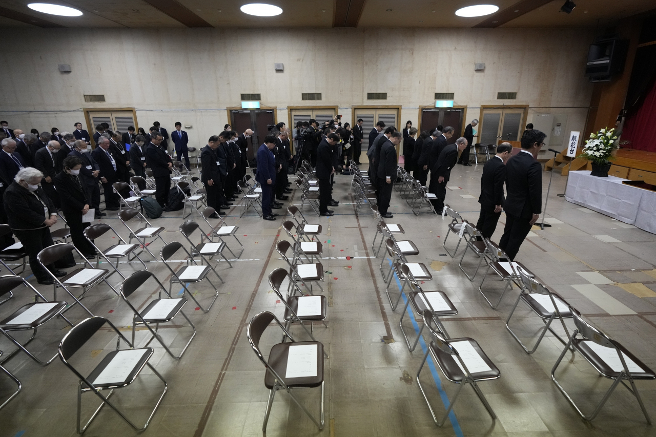 Guests offer a moment of silence during a memorial ceremony for the Sado Island Gold Mine in Sado, Niigata prefecture, Japan, as several seats reserved for South Korean guests remained empty Sunday. AP