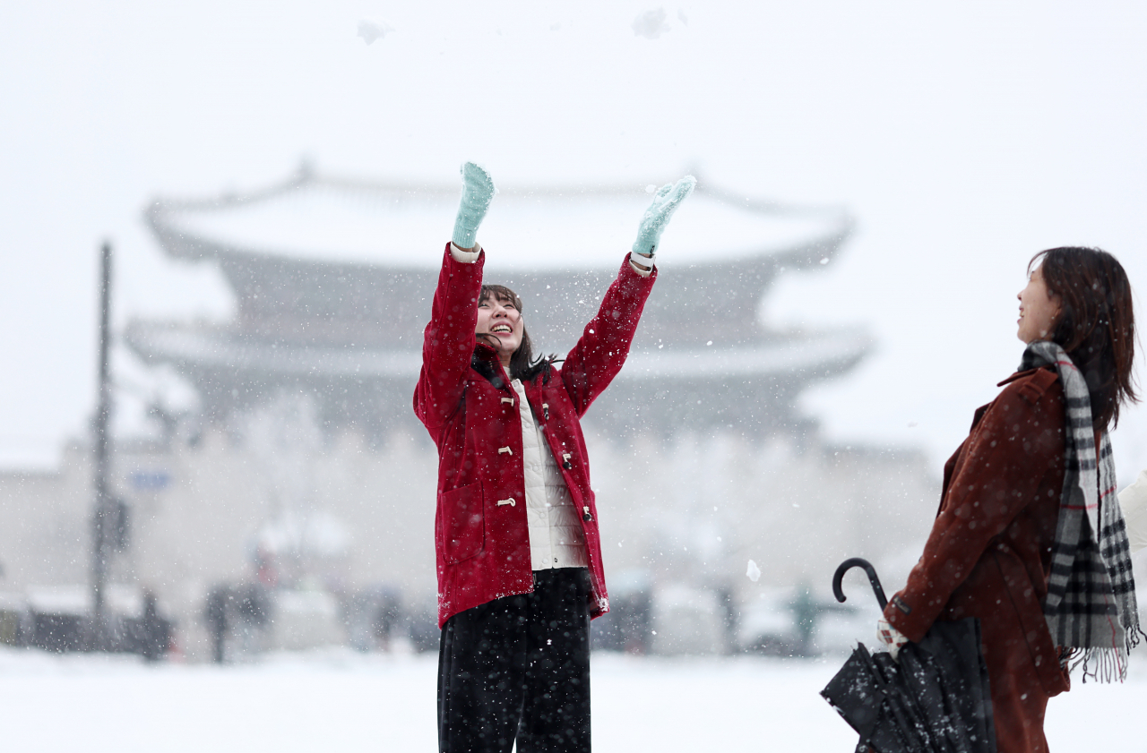 Two civilians play in the snow near Gwanghwamun Square in Jongno-gu, central Seoul, Wednesday, amid a heavy snow alert issued in the capital. (Yonhap)