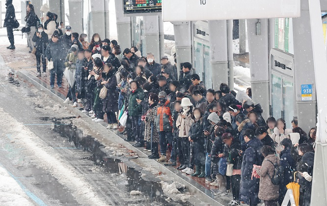 People wait for buses at a bus stop at Suwon Station amid heavy snowfall on Thursday (Yonhap)