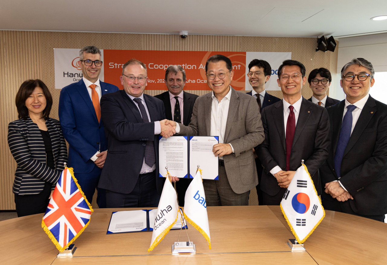 Hanwha Ocean CEO and President Kim Hee-cheol (third from right), Babcock International CEO David Lockwood (third from left) and other executives, including UK’s Second Sea Lord Nick Hine and Mark Goldsack, managing director of business growth and AUKUS at Babcock, pose for a photo after signing a partnership agreement at Hanwha Ocean headquarters in Geoje, South Gyeongsang Province, Thursday. (Hanwha Ocean)