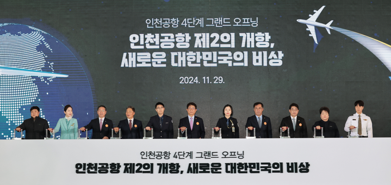 Land Minister Park Sang-woo (sixth from left), Incheon Mayor Yoo Jeong-bok (third from left), and Incheon International Airport Corporation CEO Lee Hak-jae (fourth from left), along with other officials, pose during the grand opening ceremony for the fourth-phase expansion at Incheon International Airport's Terminal 2 on Friday.