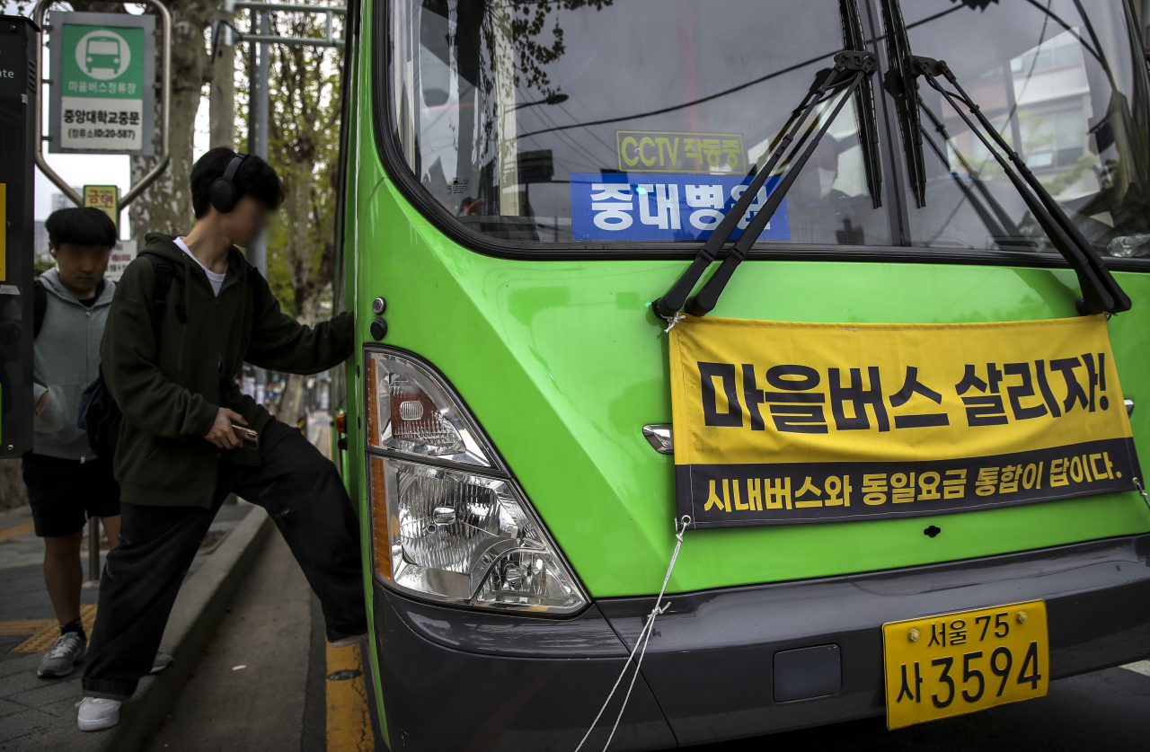 A banner reading “Save the Village Bus” is displayed on a bus passing through Seoul on Nov. 23, 2023. (Newsis)