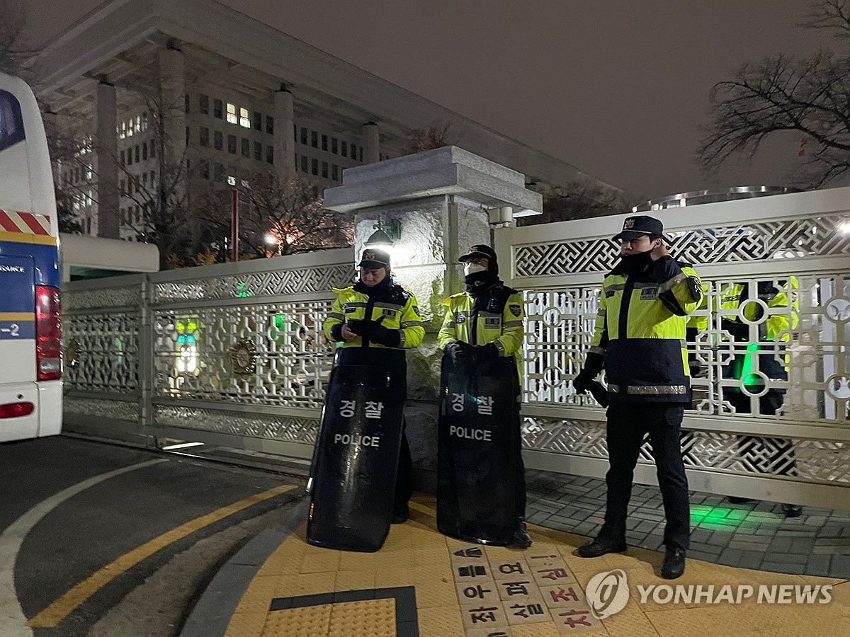 Police officials guard a gate to the National Assembly building in Seoul on Tuesday, after President Yoon Suk Yeol declared martial law and opposition leaders called on its lawmakers to gather at the parliament. (Yonhap)