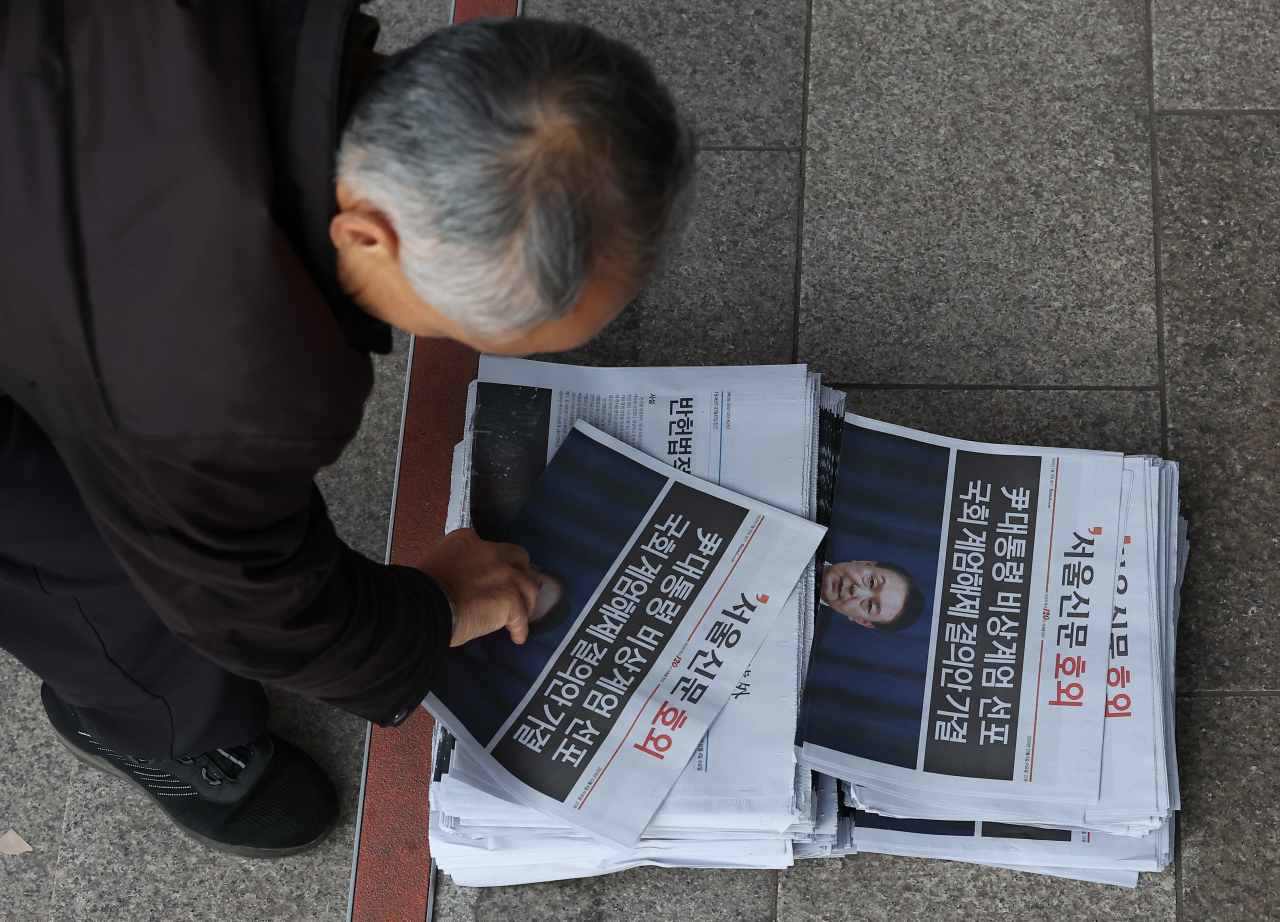 A man picks up an emergency public address issue the morning after President Yoon Seok Yeol declared the lifting of a martial law. (Yonhap)