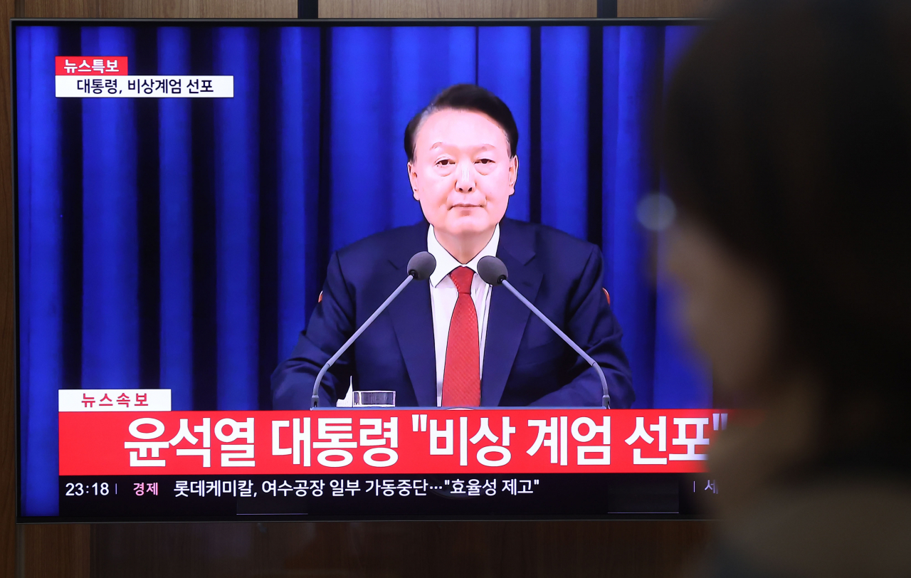 A citizen watches President Yoon Suk Yeol declare martial law on Tuesday night at Seoul Staion. (Yonhap)