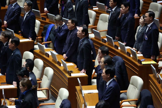 Democratic Party of Korea lawmakers look solemn and disappointed as they watch ruling People Power Party lawmakers leave the National Assembly chamber before the parliament proceeds with the vote on the impeachment motion against President Yoon Suk Yeol on Saturday. (Yonhap)