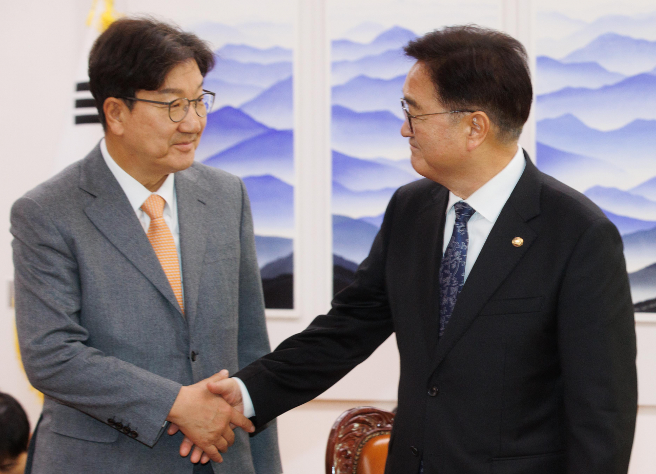 Rep. Kweon Seong-dong (left), floor leader of the ruling People Power Party, and National Assembly Speaker Rep. Woo Won-shik shake hands at at meeting at the National Assembly on Friday. (Pool photo via Yonhap)