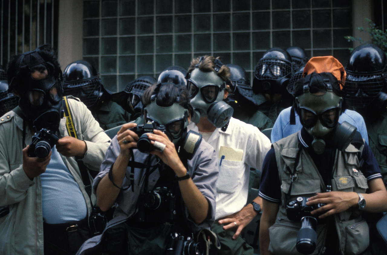 Press photographers wear gas masks during the demonstration commemorating the Gwangju uprising on May 18, 1986, South Korea. (Getty Images