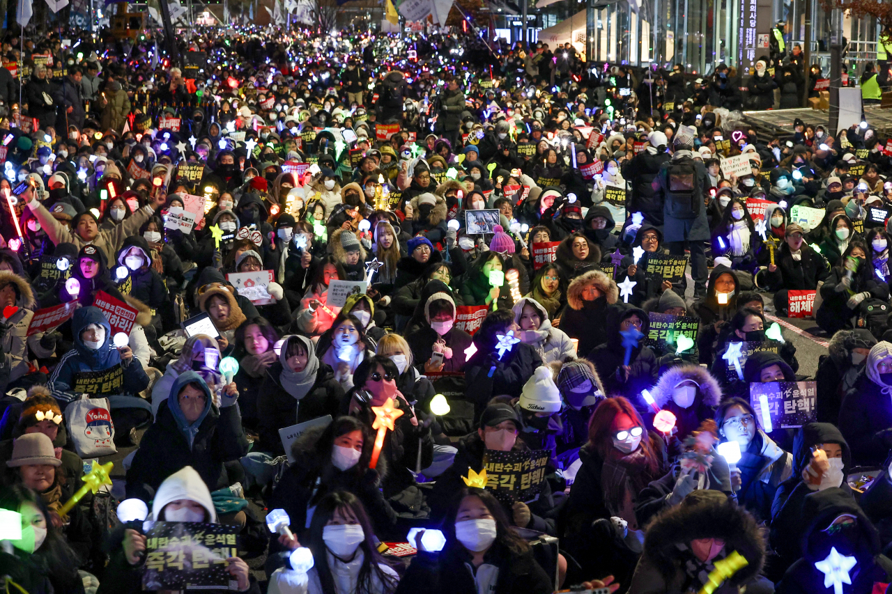 Protestors holds picket signs and light sticks during the candlelight vigil held in front of the National Assembly in western Seoul, Friday. (Yonhap)