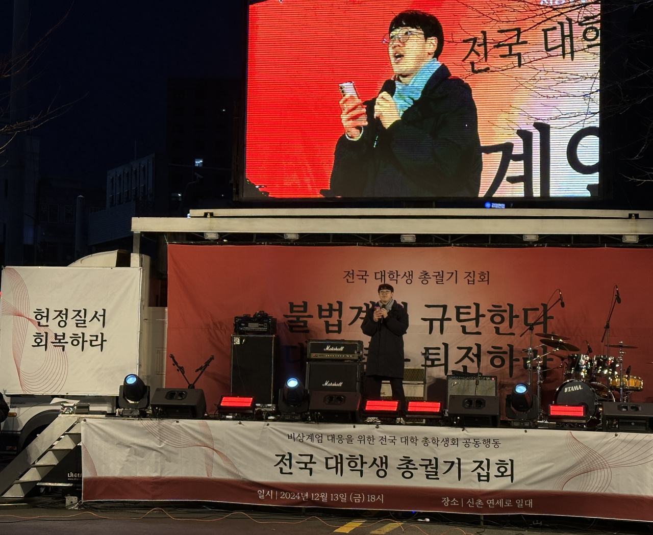 A student speaks to the crowd on stage during a mass rally led by university students on Friday protesting against President Yoon Suk Yeol and his short-lived martial law declaration in early December. (Lee Jung-joo/The Korea Herald)