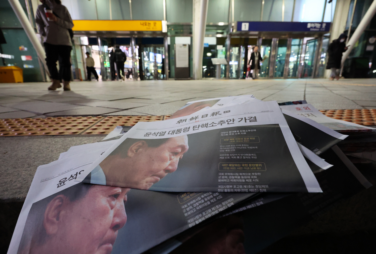 Extra edition newspapers with the top headline "President Yoon Suk Yeol's impeachment passed" are seen at Seoul Station on Saturday. (Yonhap)