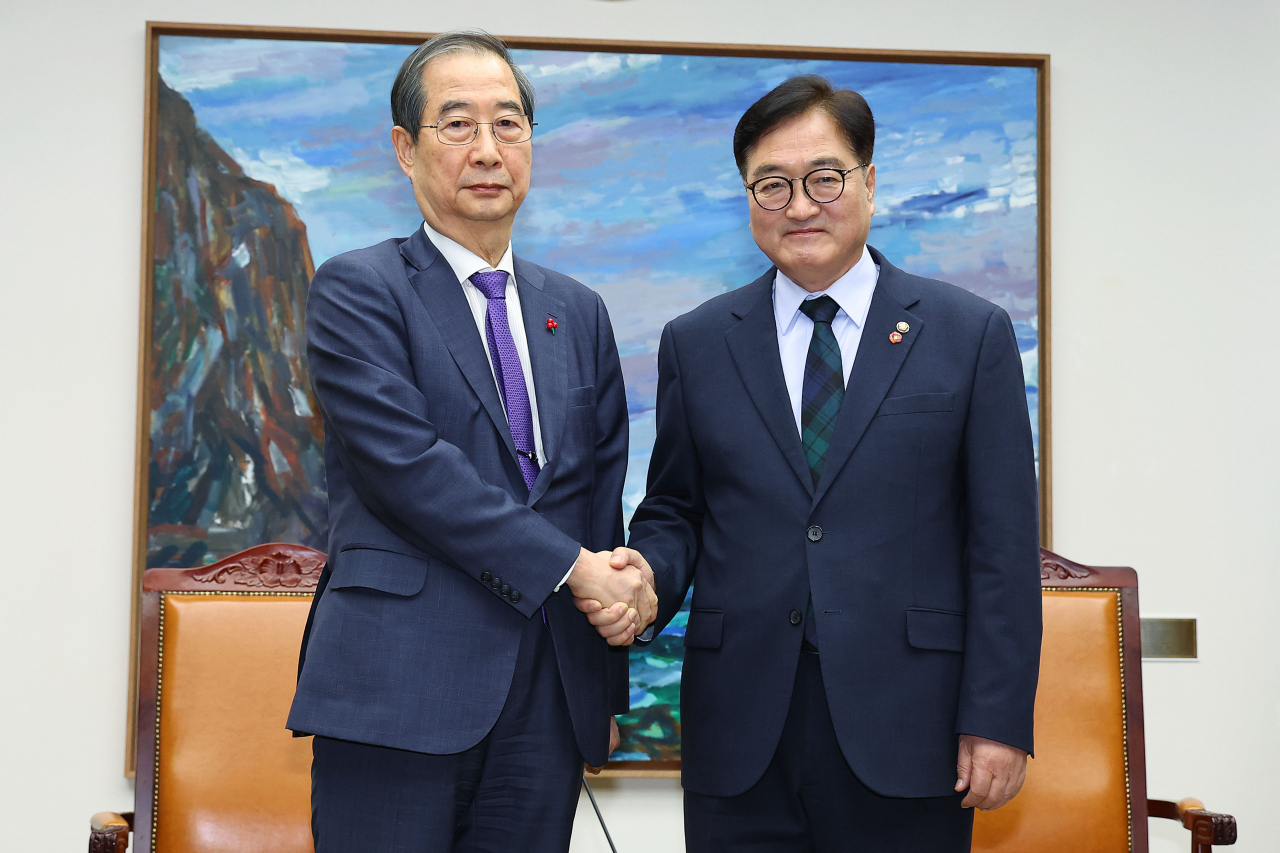 Acting President Han Duck-soo shakes hands with National Assembly Speaker Woo Won-shik at the National Assembly in western Seoul on Sunday. Yonhap