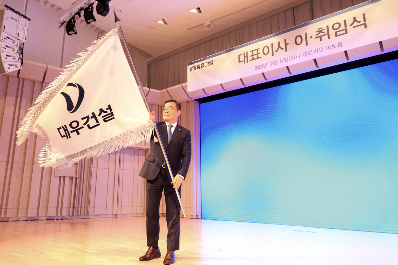 Daewoo E&C CEO Kim Bo-hyun waves a corporate flag at a ceremony held at the company's headquarters in Seoul on Tuesday. (Daewoo E&C)